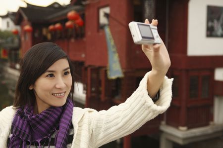 Woman taking picture of herself using digital cameraの写真素材