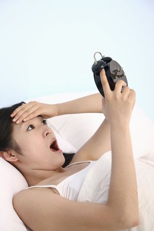 Overslept woman, shocked looking at alarm clockの写真素材