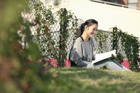 Woman reading book outdoorsの写真素材