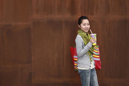 Woman with bag holding a cup of drinkの写真素材
