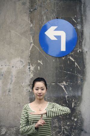 Woman showing hand signal, traffic sign on the backgroundの写真素材
