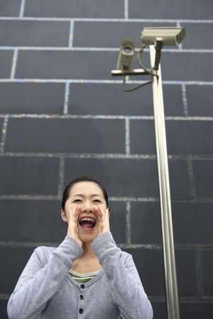 Woman with hands cupped at the side of her mouth, shouting
