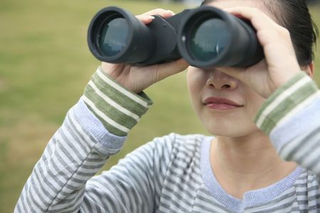 Woman looking through binocularsの写真素材