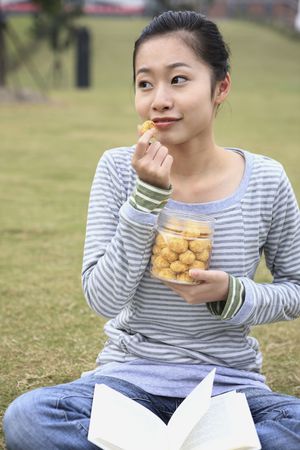 Woman enjoying cookies with book on her lapの写真素材