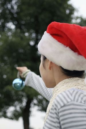 Woman with Christmas hat holding Christmas ornamentの写真素材