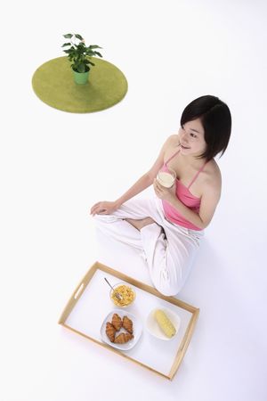 Woman holding a glass of milk with breakfast tray at her sideの写真素材