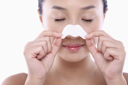 Young woman peeling off pore strips from her noseの写真素材