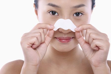 Young woman peeling off pore strips from her noseの写真素材