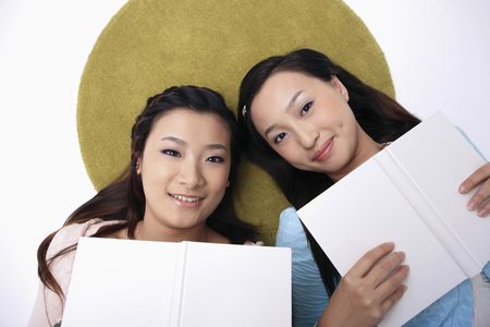 Beautiful young women lying on the floor, holding booksの写真素材