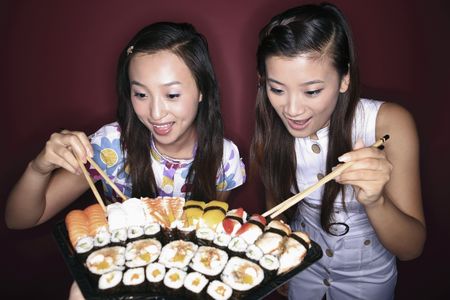 Young women looking at the variant of sushiの写真素材