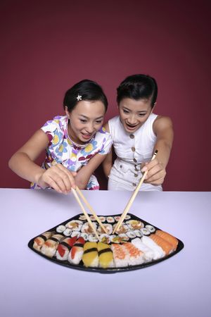 Young women taking sushi with chopsticksの写真素材