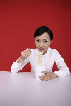 Young woman enjoying a cup of instant noodleの写真素材