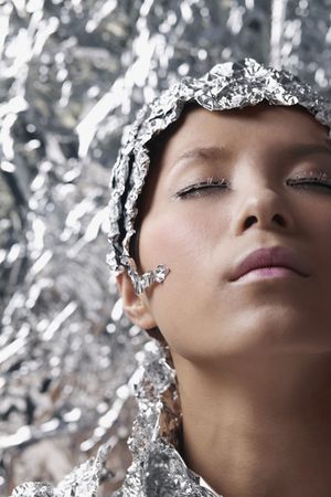 Woman wearing foil accessories among foil backgroundの写真素材