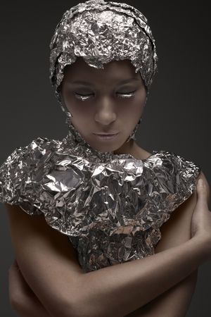 Woman wearing foil accessories embracing herselfの写真素材