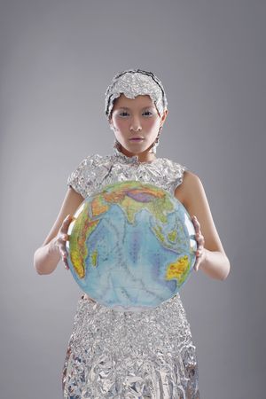 Woman wearing foil accessories holding globeの写真素材