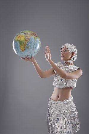 Woman wearing foil accessories holding globeの写真素材