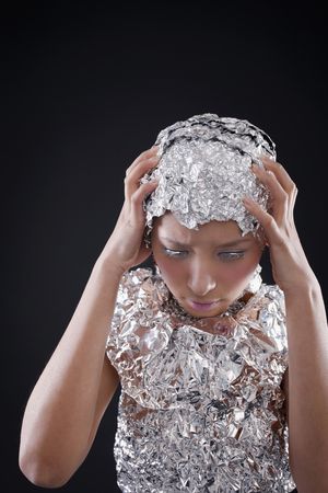 Woman wearing foil accessories with head in her handsの写真素材