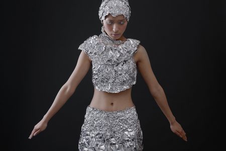Woman wearing foil accessories with head bent downの写真素材