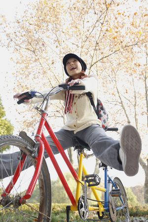 Woman riding tandem bicycle with legs outstretchedの写真素材