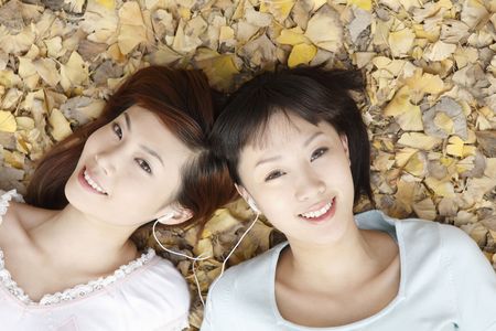 Women lying on the ground listening to music on portable MP3 playerの写真素材