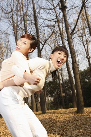 Woman carrying her friend on her backの写真素材