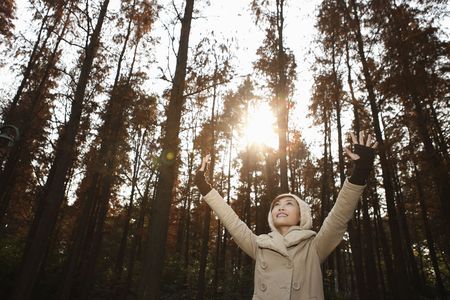 Woman in warm clothing raising her handsの写真素材
