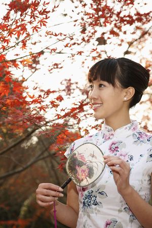 Woman in cheongsam holding fanの写真素材