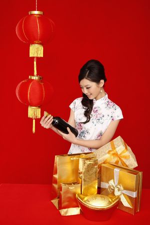 Woman in cheongsam checking out bottle of wineの写真素材