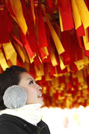 Woman with ear muff standing under a wishing treeの写真素材