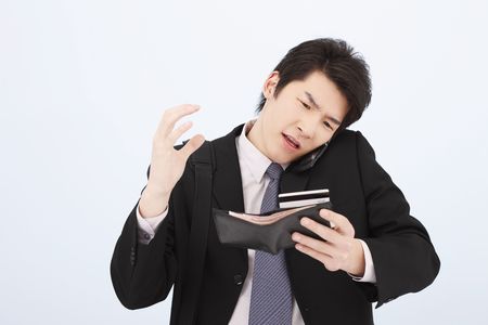 Man referring to his credit card while talking on the phoneの写真素材