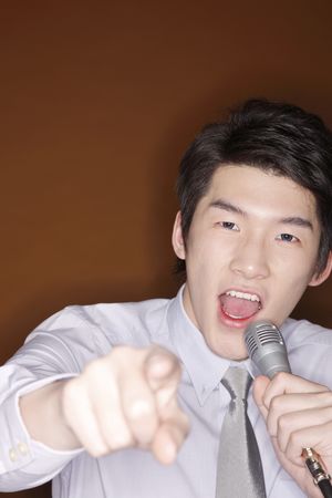 Man pointing at the camera while singing into the microphoneの写真素材