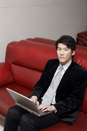 Man sitting on couch using laptopの写真素材