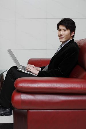 Man sitting on couch using laptopの写真素材
