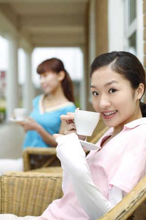Young women drinking coffee on porchの写真素材