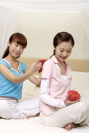 Young woman measuring her friend's back while knittingの写真素材
