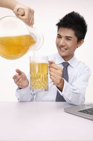 Hand pouring a jug of beer into businessman's glassの写真素材