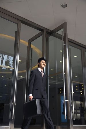 Businessman with briefcase walking out of a buildingの写真素材