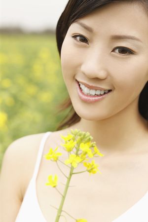 Woman holding oilseed rape, smiling