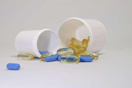 Small and large bottle of pills on a white background in two colours.の写真素材