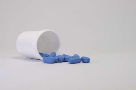 Bottle of pills spread around on a white background.