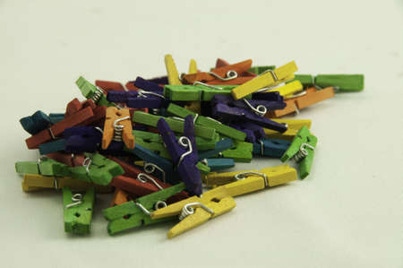 Miniture clothes pegs on a white background they are different colors.