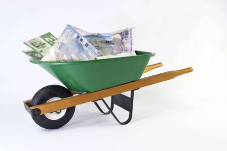 Wheel barrel full of dollars on a white background.の写真素材