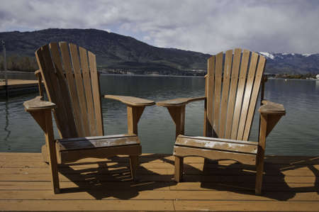 Two adirondack chairs on the dock.