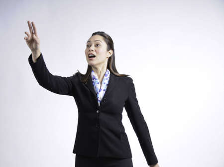 A young woman hailing a cab by the way she has her hand out strecthed.She is of mixed  ethnicity.の写真素材