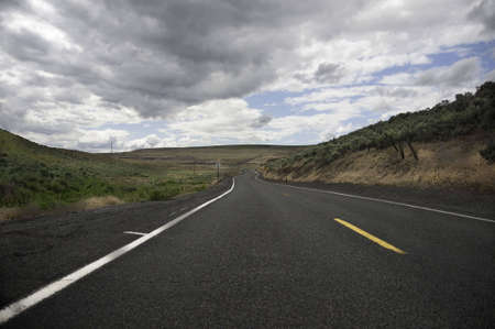 Low view of the road ahead dark clouds above.の写真素材