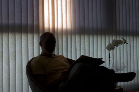 man sitting and reading next to windowの写真素材