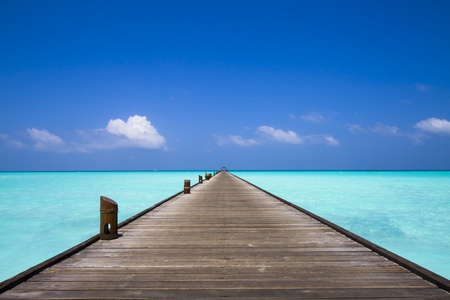 endless jetty to the horizon; view to a turquoise sea and blue sky with white cloudsの写真素材