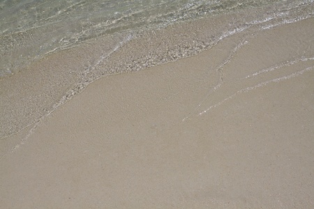 background with little wave and brown sand from the beachの写真素材