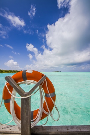 life belt at the sea with island blue sky and cloudsの写真素材