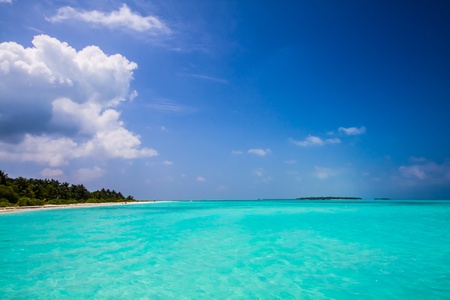 tropical island with long beach, palms, blue sky, turquoise, sea, maldivesの写真素材